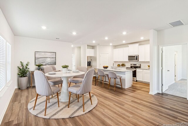 dining room featuring a wealth of natural light, sink, and light wood-type flooring