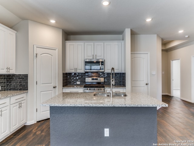 kitchen featuring appliances with stainless steel finishes, dark hardwood / wood-style floors, and a center island with sink