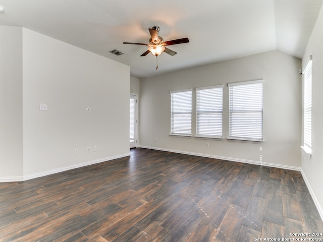 spare room with dark wood-type flooring, vaulted ceiling, a healthy amount of sunlight, and ceiling fan