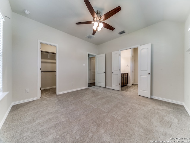 unfurnished bedroom with a spacious closet, ceiling fan, light carpet, and a closet