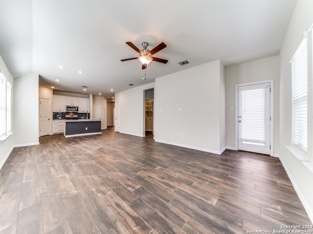 unfurnished living room with dark hardwood / wood-style floors, a healthy amount of sunlight, and ceiling fan