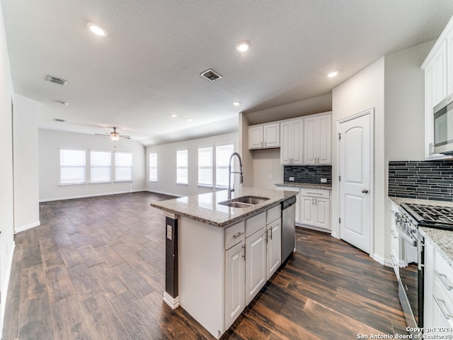 kitchen featuring appliances with stainless steel finishes, sink, white cabinets, dark wood-type flooring, and a center island with sink