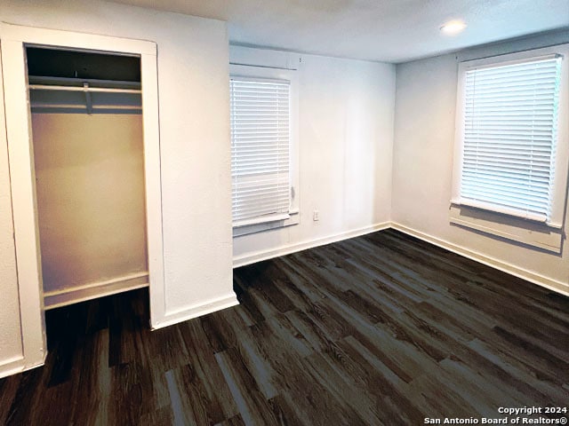 unfurnished bedroom with a closet and dark wood-type flooring