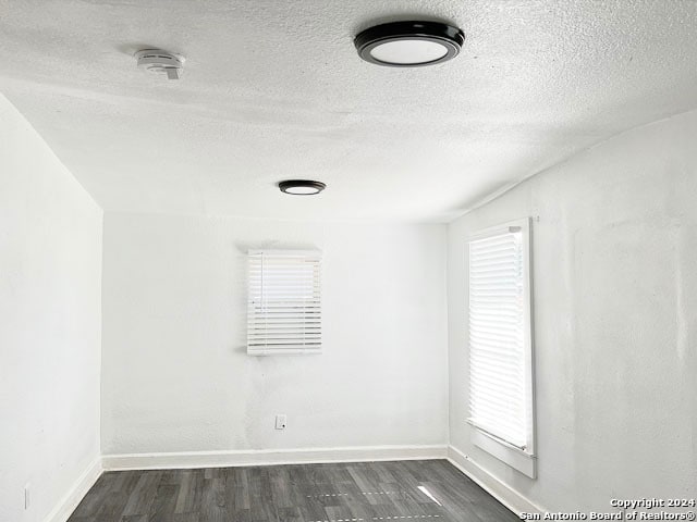 spare room with dark wood-type flooring and a textured ceiling