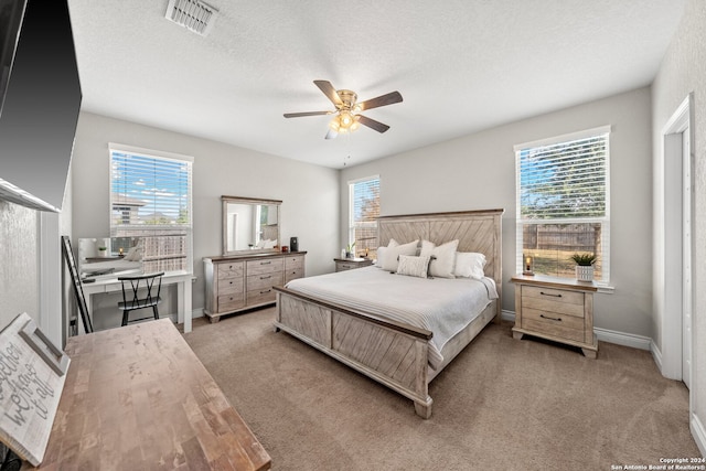 carpeted bedroom with a textured ceiling, multiple windows, and ceiling fan