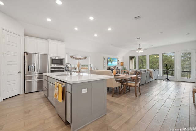 kitchen featuring stainless steel appliances, light hardwood / wood-style flooring, a center island with sink, and white cabinets