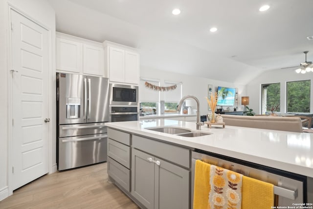 kitchen with white cabinets, light wood-type flooring, vaulted ceiling, sink, and stainless steel appliances