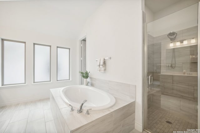 bathroom featuring independent shower and bath, vaulted ceiling, and tile patterned flooring