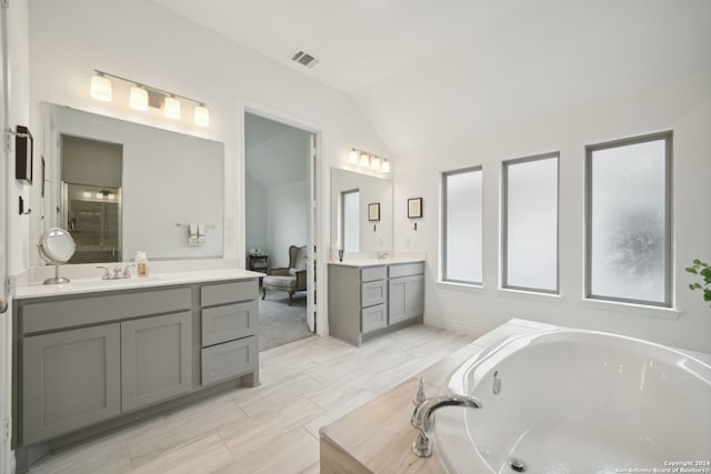 bathroom featuring vanity, lofted ceiling, and independent shower and bath