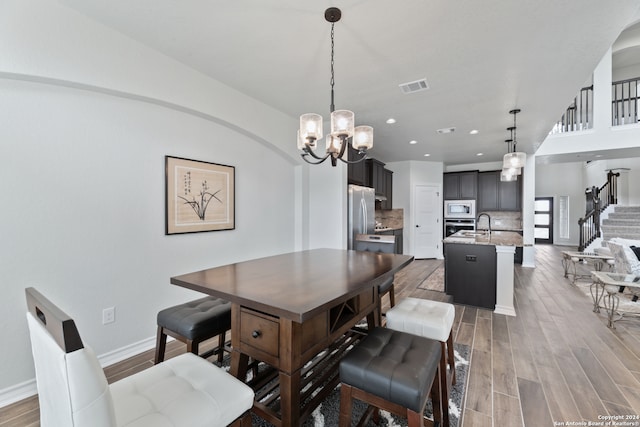 dining area with an inviting chandelier, hardwood / wood-style floors, and sink