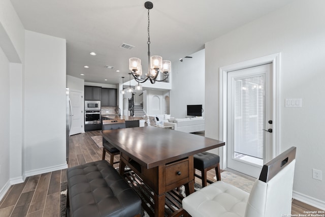 dining space with sink, dark wood-type flooring, and a notable chandelier