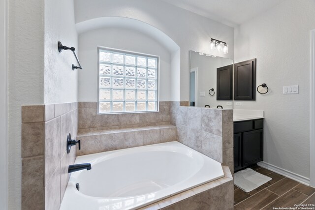 bathroom featuring vanity, tiled bath, and hardwood / wood-style flooring