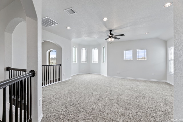 carpeted spare room featuring lofted ceiling, a textured ceiling, and ceiling fan