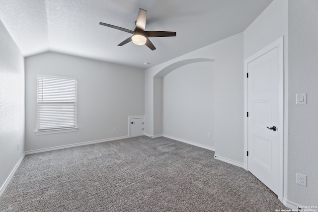 carpeted empty room with ceiling fan, a textured ceiling, and vaulted ceiling