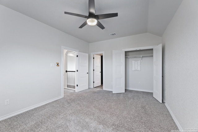 unfurnished bedroom with lofted ceiling, a closet, light colored carpet, and ceiling fan