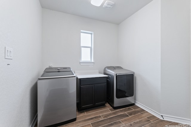 clothes washing area with dark wood-type flooring, independent washer and dryer, and cabinets