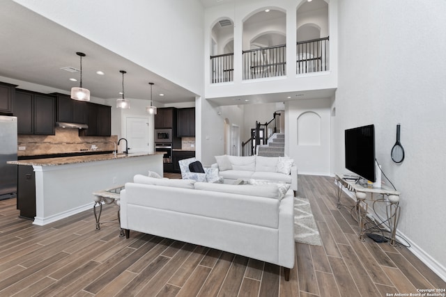 living room with sink, a towering ceiling, and dark hardwood / wood-style flooring