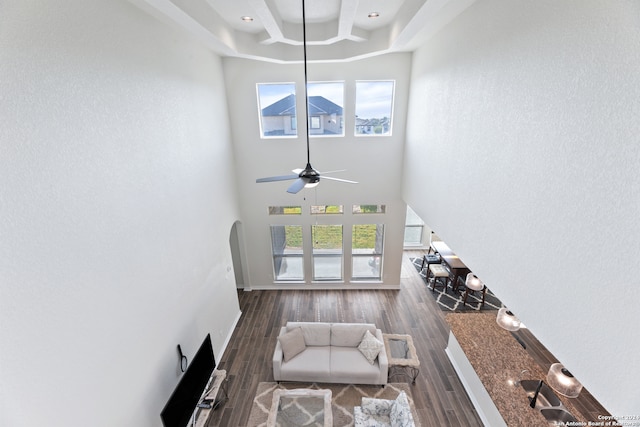 living room featuring coffered ceiling, ceiling fan, a towering ceiling, and dark hardwood / wood-style flooring