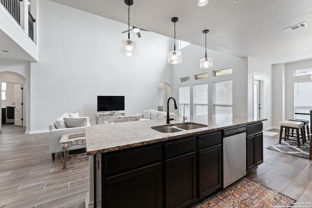 kitchen with a healthy amount of sunlight, a kitchen island with sink, sink, and hanging light fixtures