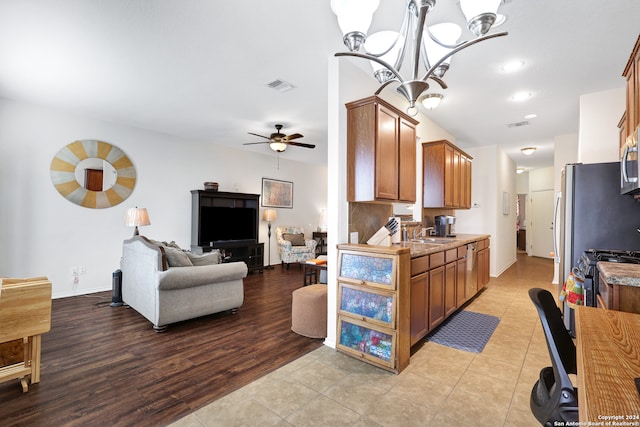 kitchen with sink, light hardwood / wood-style flooring, hanging light fixtures, and ceiling fan with notable chandelier