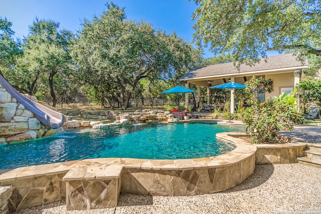 view of swimming pool featuring a patio, a water slide, and pool water feature