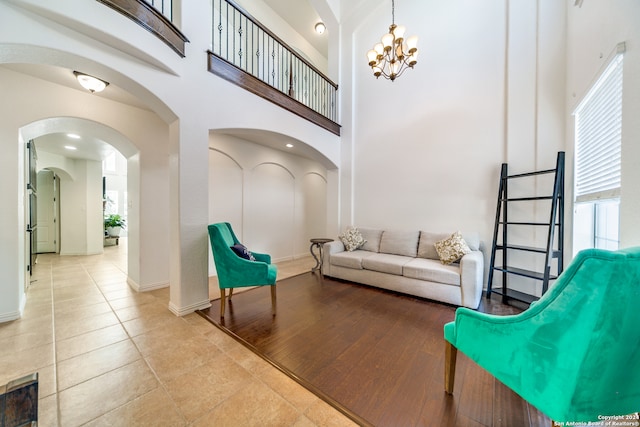 living room featuring an inviting chandelier, a high ceiling, and light hardwood / wood-style floors