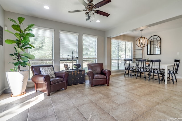 living room featuring a wealth of natural light, ceiling fan with notable chandelier, and light tile patterned floors