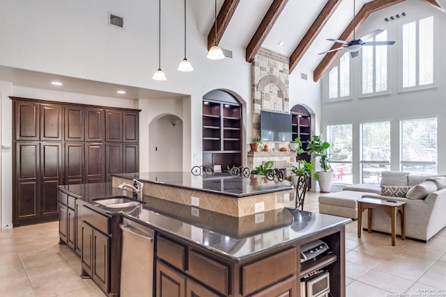 kitchen with dark brown cabinets, hanging light fixtures, an island with sink, high vaulted ceiling, and sink