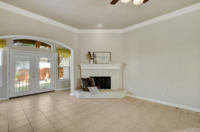 unfurnished living room featuring french doors, a brick fireplace, ceiling fan, crown molding, and light tile patterned floors