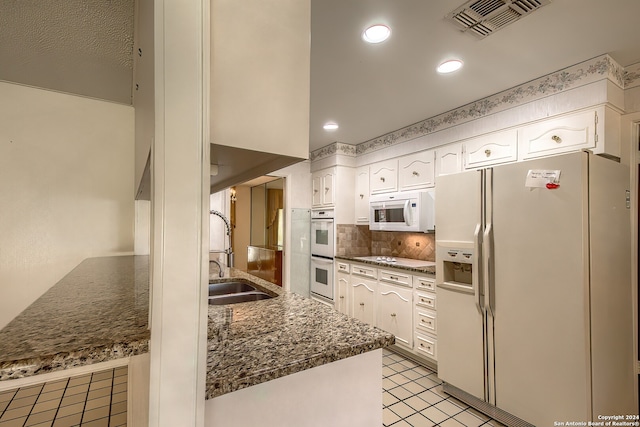 kitchen with white appliances, tasteful backsplash, sink, white cabinetry, and light tile patterned floors