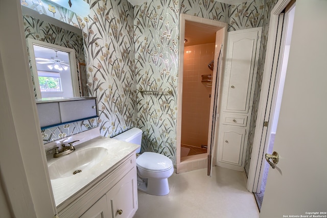 bathroom with vanity, a tile shower, toilet, and ceiling fan