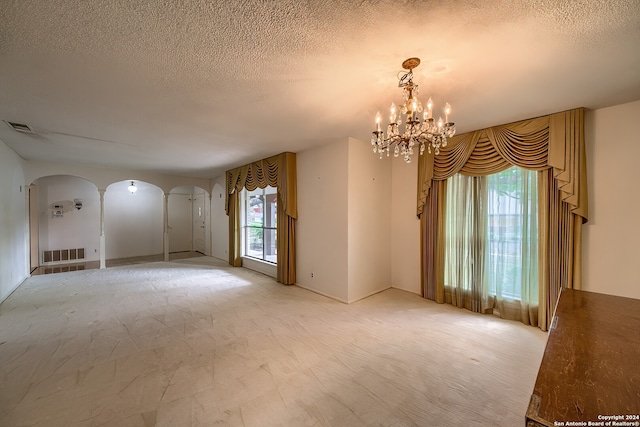 spare room featuring a textured ceiling and an inviting chandelier