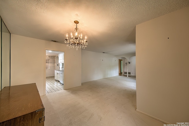 spare room with a notable chandelier and a textured ceiling