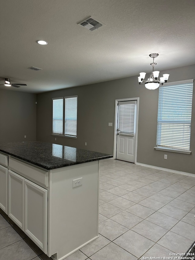 kitchen with a center island, dark stone counters, pendant lighting, and white cabinets