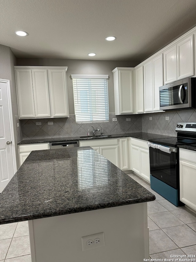 kitchen with sink, a kitchen island, appliances with stainless steel finishes, and dark stone counters