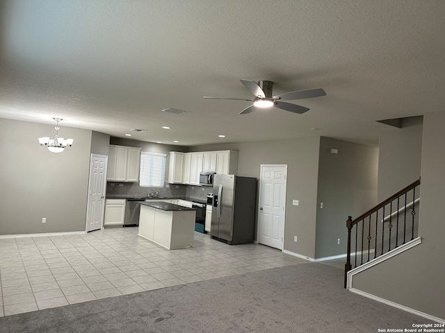 kitchen with white cabinets, appliances with stainless steel finishes, ceiling fan with notable chandelier, decorative light fixtures, and light colored carpet