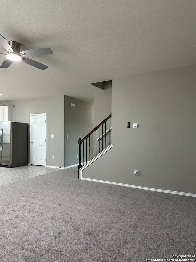 unfurnished living room featuring ceiling fan, a textured ceiling, and light colored carpet