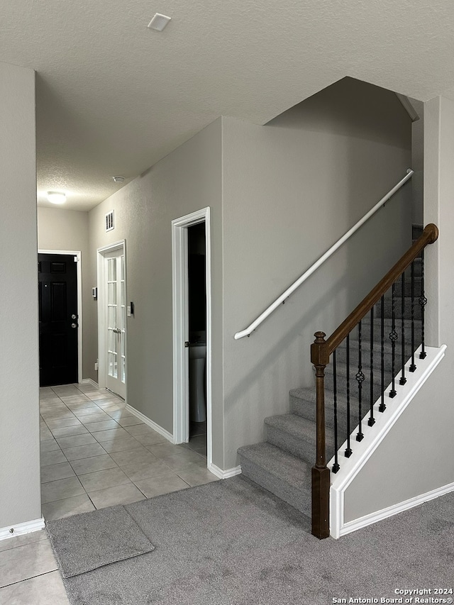 stairs featuring a textured ceiling and carpet