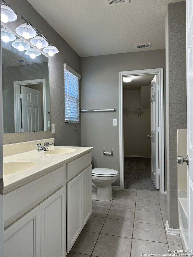 bathroom featuring tile patterned floors, a tub, toilet, vanity, and a textured ceiling