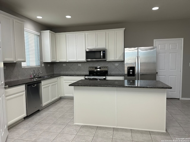 kitchen featuring a center island, appliances with stainless steel finishes, white cabinets, and dark stone countertops