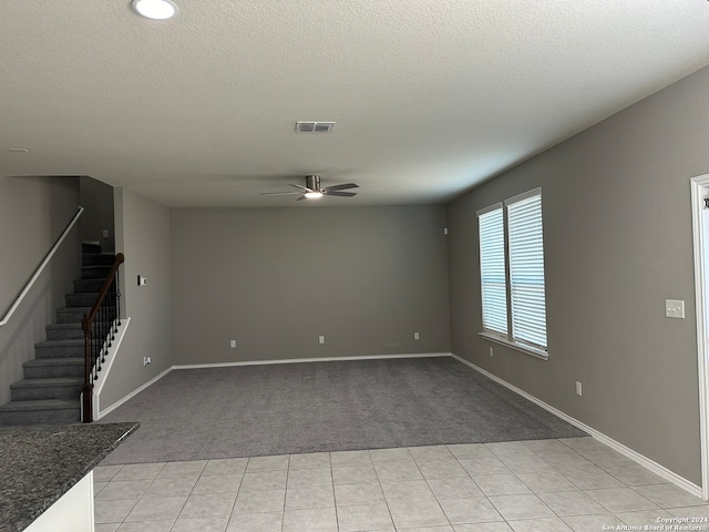 unfurnished living room featuring ceiling fan, a textured ceiling, and light colored carpet