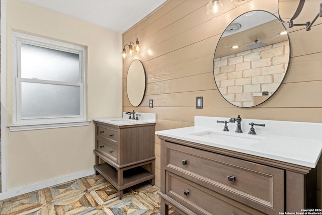 bathroom with a textured ceiling, vanity, and wood walls