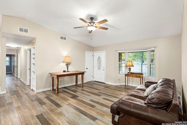 living room with hardwood / wood-style floors, a textured ceiling, ceiling fan, and lofted ceiling