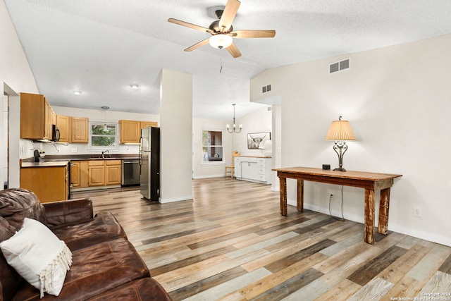 living room featuring ceiling fan with notable chandelier, lofted ceiling, sink, and light hardwood / wood-style flooring