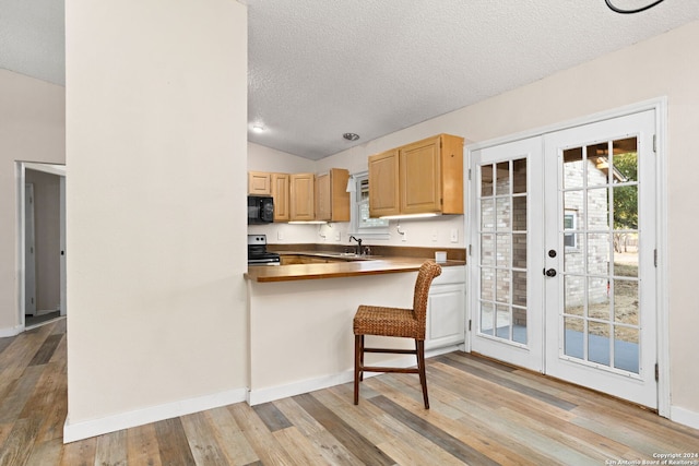 kitchen featuring french doors, stainless steel electric stove, a textured ceiling, a kitchen bar, and kitchen peninsula