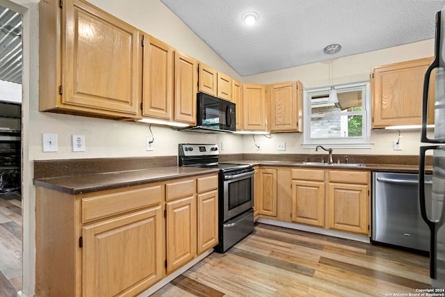 kitchen featuring light brown cabinetry, stainless steel appliances, vaulted ceiling, sink, and light hardwood / wood-style flooring