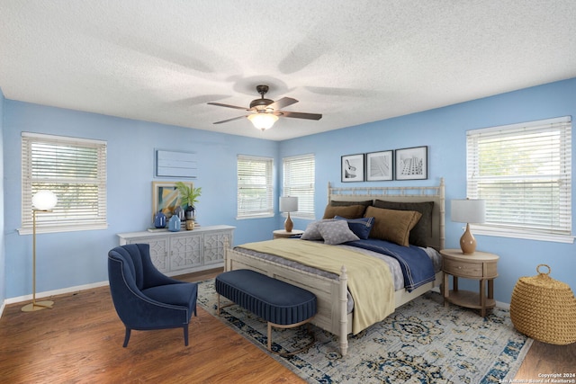 bedroom featuring multiple windows, ceiling fan, hardwood / wood-style floors, and a textured ceiling