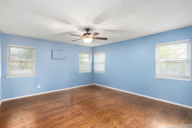 empty room featuring ceiling fan, dark hardwood / wood-style flooring, and a healthy amount of sunlight