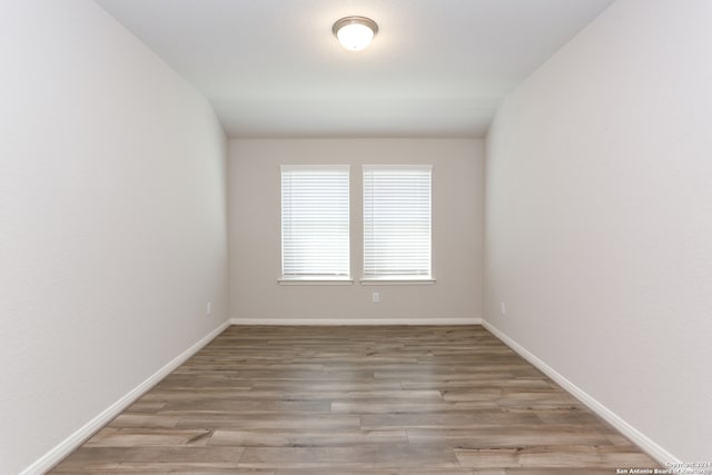 spare room with hardwood / wood-style flooring and vaulted ceiling