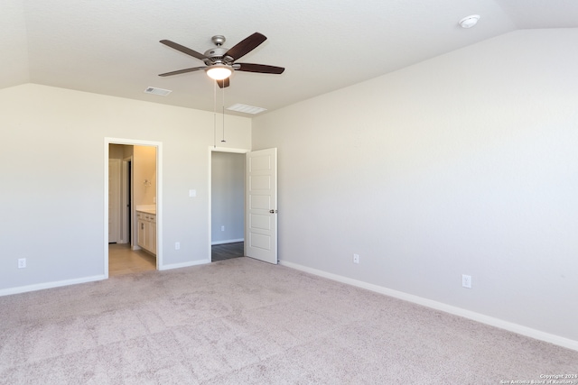 unfurnished bedroom featuring vaulted ceiling, ensuite bathroom, light colored carpet, and ceiling fan